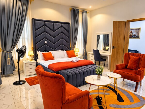 A modern hotel room with a large bed, a desk, a chair, and a small table. - Fortified 4 Bedroom Home (Lekki)