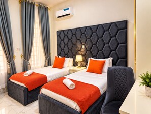 A hotel room with two beds, a modern headboard, a bedside lamp, and an air conditioning unit. - Fortified 4 Bedroom Home (Lekki)