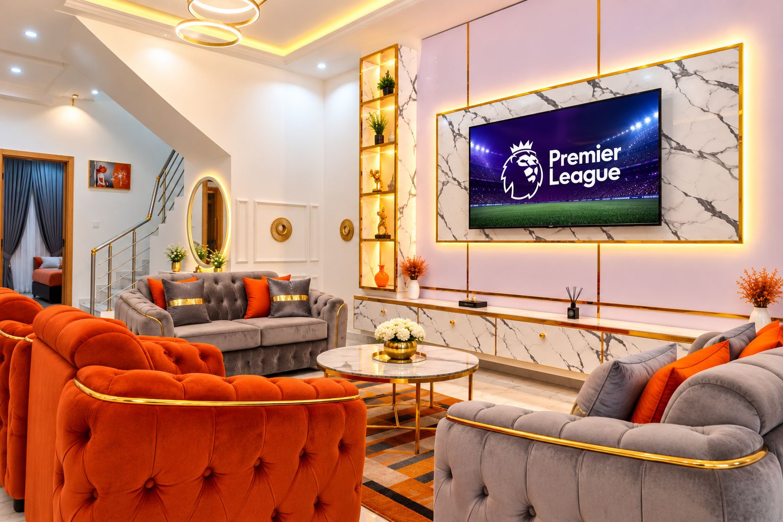 Una sala de estar moderna con un televisor grande mostrando el logo de la Premier League, un sofá gris, sillones naranja y una pared con estampado de mármol.