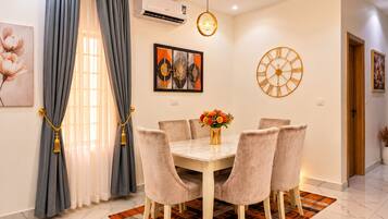 Un comedor con una mesa de mármol, sillas acolchadas, un tapete estampado y un reloj de pared.