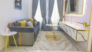 A modern living room with a sofa, a round coffee table, a small side table, and a marble-patterned rug. - Fortified 4 Bedroom Home (Lekki)