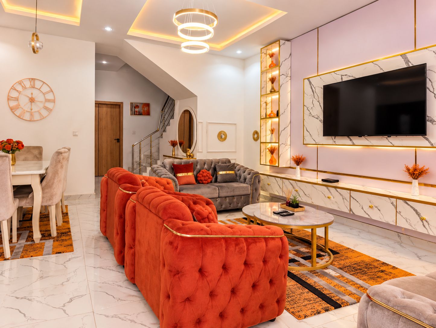 A modern living room with a sectional sofa, a round coffee table, and a TV mounted on the wall.