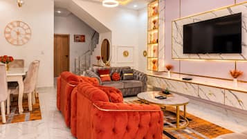 A modern living room with a sectional sofa, a round coffee table, and a TV mounted on the wall.