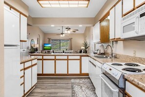 A modern kitchen with white cabinets, a granite countertop, a stove, and a ceiling fan. - Newly Available Cozy & Clean Condo!  1 mile from Branson strip! Premier Hosts! (Branson)
