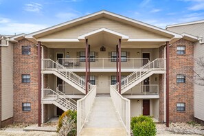 Un immeuble d’appartements à plusieurs étages, doté d’une entrée centrale, de deux balcons par étage et d’une façade en briques.