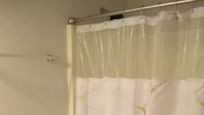 Une salle de bain avec des toilettes, un rideau de douche et un tapis de sol.