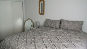 Une chambre à coucher avec un lit, un miroir et une porte.