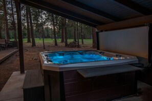 A hot tub under a covered area with a view of a forest.