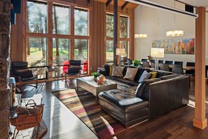 A spacious living room with a large sectional sofa, a coffee table, and a dining area with chairs.
