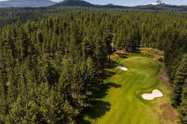 A golf course surrounded by dense forest with multiple sand bunkers. - Welcoming Lodge Home: 6BR, Sleeps 14, Hot Tub (Sisters)