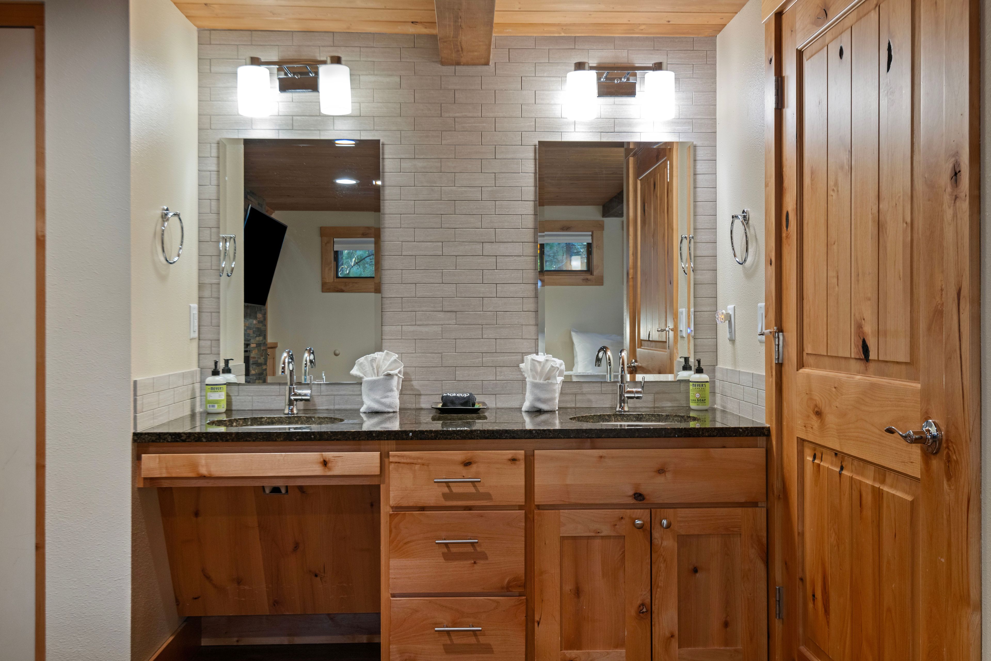 A bathroom with a double sink, wooden cabinets, and a large mirror.