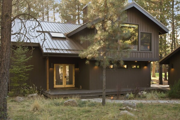 A cabin with a sloped roof, a front door with glass panels, and a small porch area.