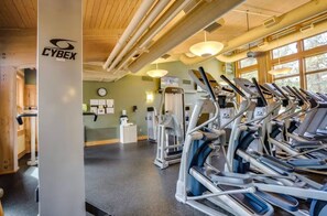 A gym with exercise equipment, a clock on the wall, and a wooden ceiling. - Welcoming Lodge Home: 6BR, Sleeps 14, Hot Tub (Sisters)
