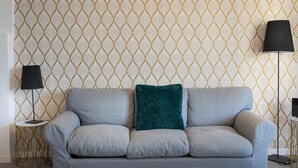 A grey sofa with a teal pillow against a patterned wallpaper. - Rental in Rome Vatican Secret Apartment (Rome)