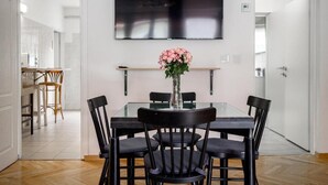 A dining area with a glass table, black chairs, and a vase with flowers. - The Vlasta Collection (Zagreb)