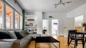 A modern living room with a sofa, coffee table, and dining area. - The Vlasta Collection (Zagreb)