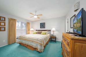 A bedroom with a bed, a ceiling fan, a dresser, and a television. - Innsbrook Vacation Townhome 121 (Ruidoso)