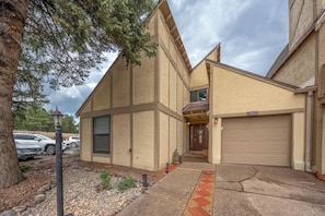 A two-story building with a garage, a front entrance, and a pathway leading to the door.