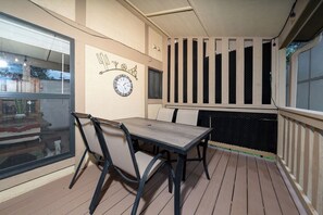 En täckt uteplats med ett bord och stolar, en väggklocka och en dekorativ väggpanel.