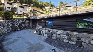 A stone wall with a wooden building featuring a scenic mural. - House Scacciapensieri (Pozza di Fassa)
