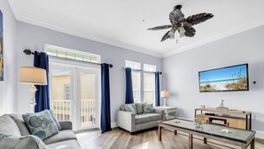 A spacious living room with a grey sofa, a coffee table, and a television on a wooden stand. - ☀️Pet Friendly | Pool | Walk to Beach Access | Livin' La Villa Loca☀️ (Panama City Beach)