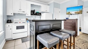 Una cocina moderna con armarios blancos, encimera negra y dos taburetes de bar.