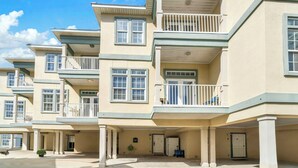 Una hilera de edificios residenciales de varios pisos, con balcones, un vestíbulo cubierto y cielo despejado.
