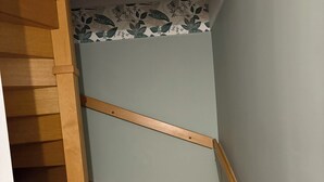 Un escalier en bois, doté d’une rampe, mène à un palier dont le mur est décoré d’un motif floral.