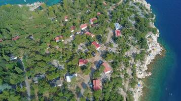 Vista aérea de un pueblo costero con casas, aguas azul turquesa y terreno rocoso.