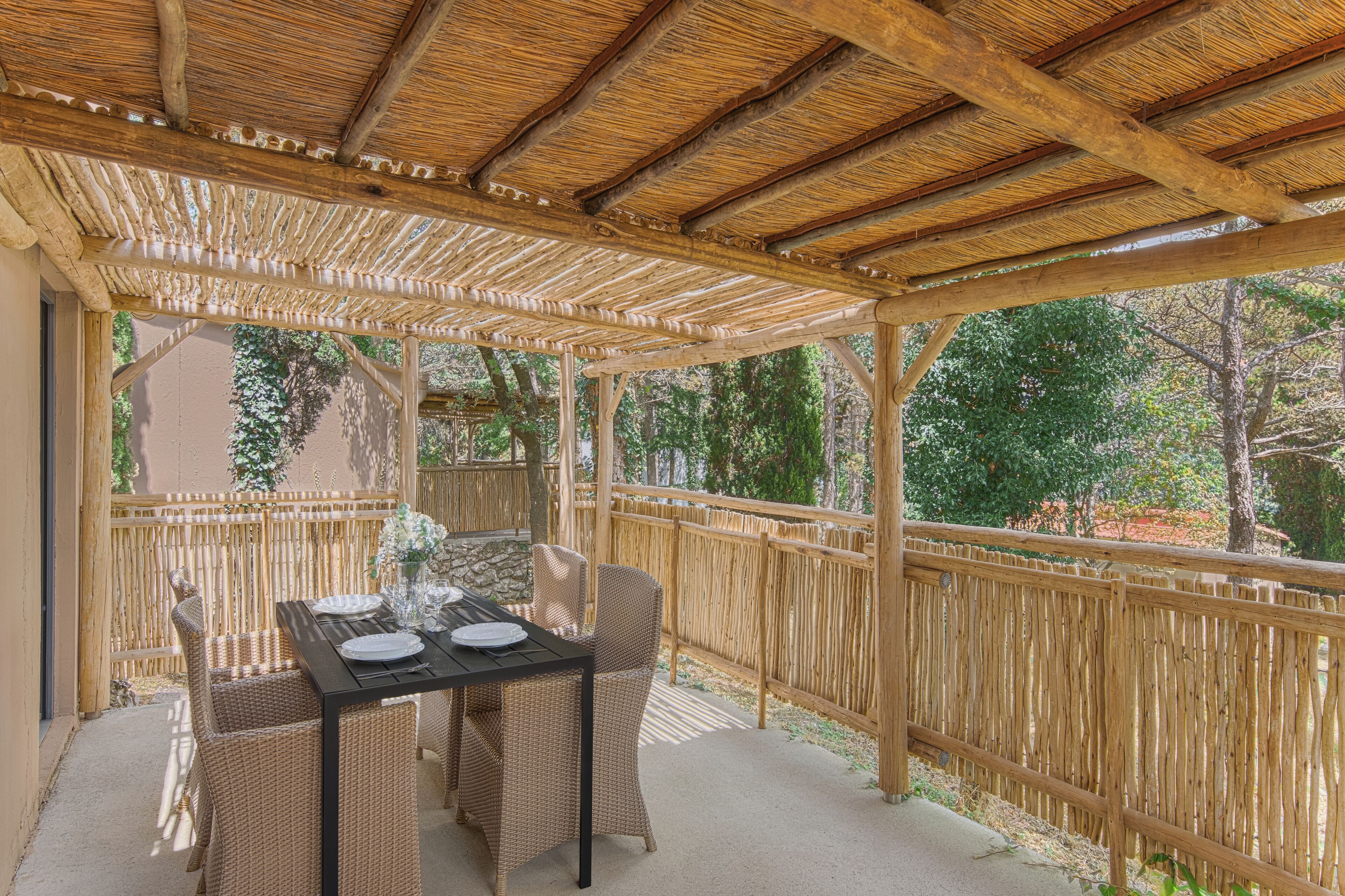 A covered outdoor seating area with wicker furniture and a table set for two.