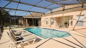 A covered swimming pool with lounge chairs and a patio area. - Cozy 4 Bedroom Villa with 3 Bathrooms and South Facing Pool (CLERMONT)