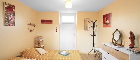 Un dormitorio con cama, mesita de noche, cómoda y una puerta que da a otra habitación.