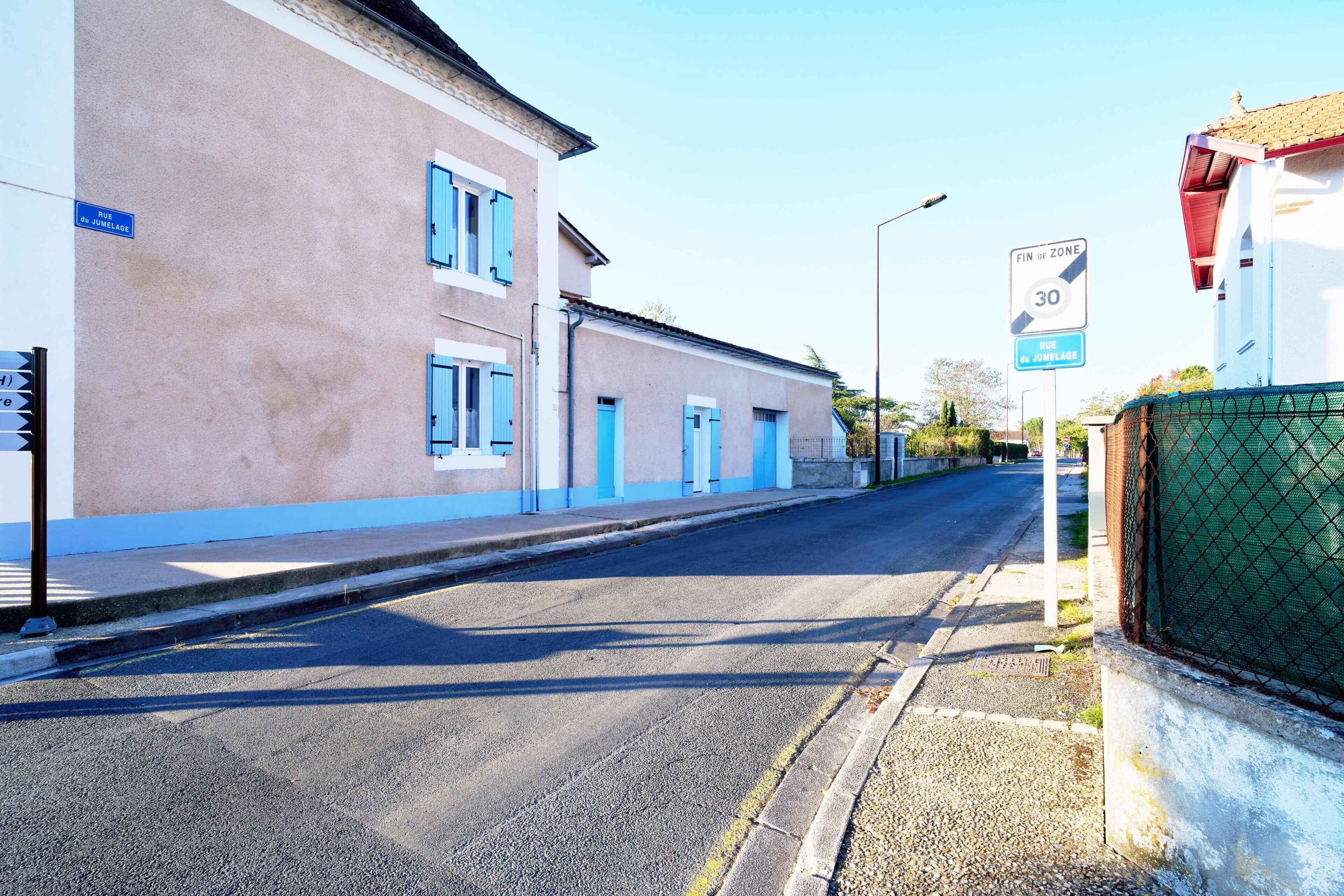 A street with buildings, a speed limit sign, and a sign indicating the end of a zone.