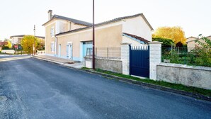 A two-story house with a blue door, a gated driveway, and a street view.