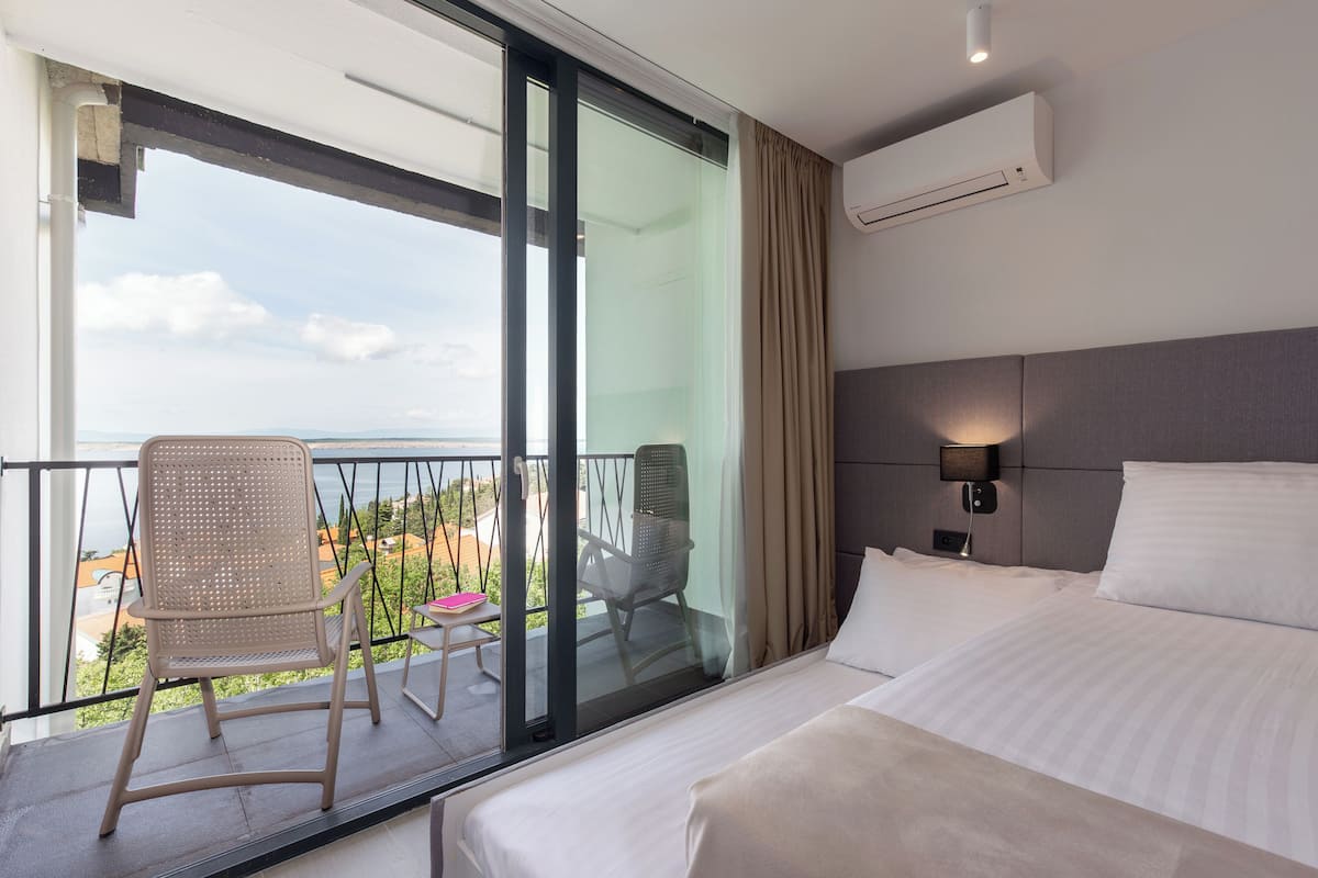 Habitación de hotel con balcón, cama, silla y mesa.