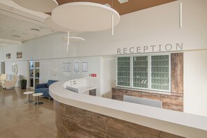 A reception area with a counter, seating, and a reception desk. - Paviljoni Omorika (Crikvenica)