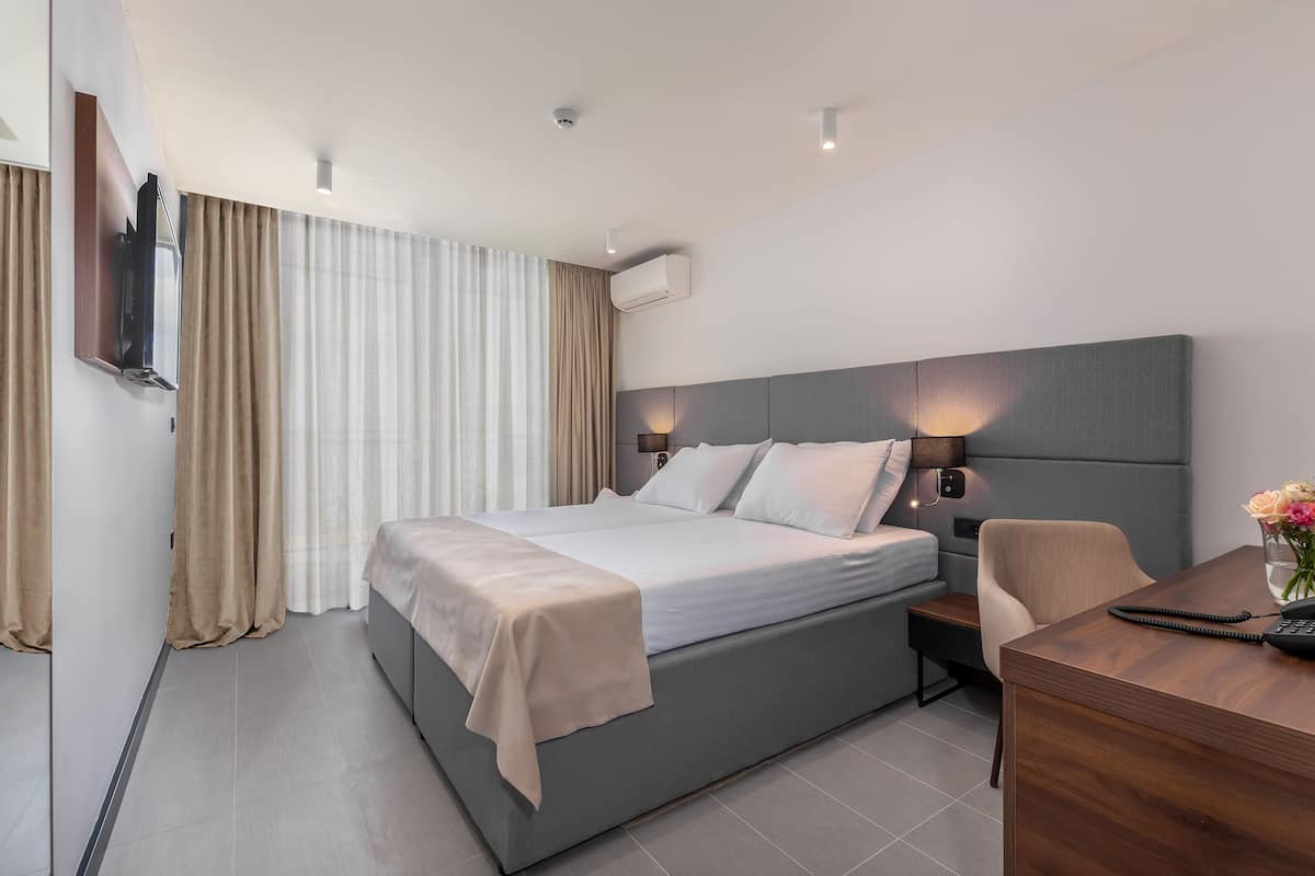 Una habitación de hotel moderna con una cama grande, un escritorio y una silla.