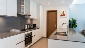 A modern kitchen with white cabinets, stainless steel appliances, a built-in oven, a microwave, and a sink. - City Walk 1BR Near Burj Khalifa Dubai Mall (Dubai)