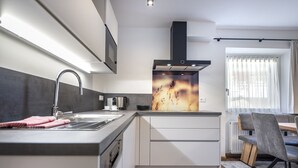 Eine moderne Küche mit einer Edelstahl-Spüle, einer Kaffeemaschine und einem großen Fenster mit Vorhängen.