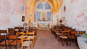 An interior of a church with wooden pews arranged in rows, a central altar, and a vaulted ceiling.