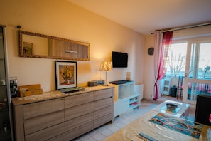 Una sala moderna con un aparador de madera, un televisor de pantalla plana, un sofá y un comedor con mesa y sillas.