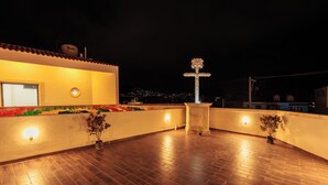 Una terraza en la azotea con una fuente, plantas en macetas y una pared bien iluminada.