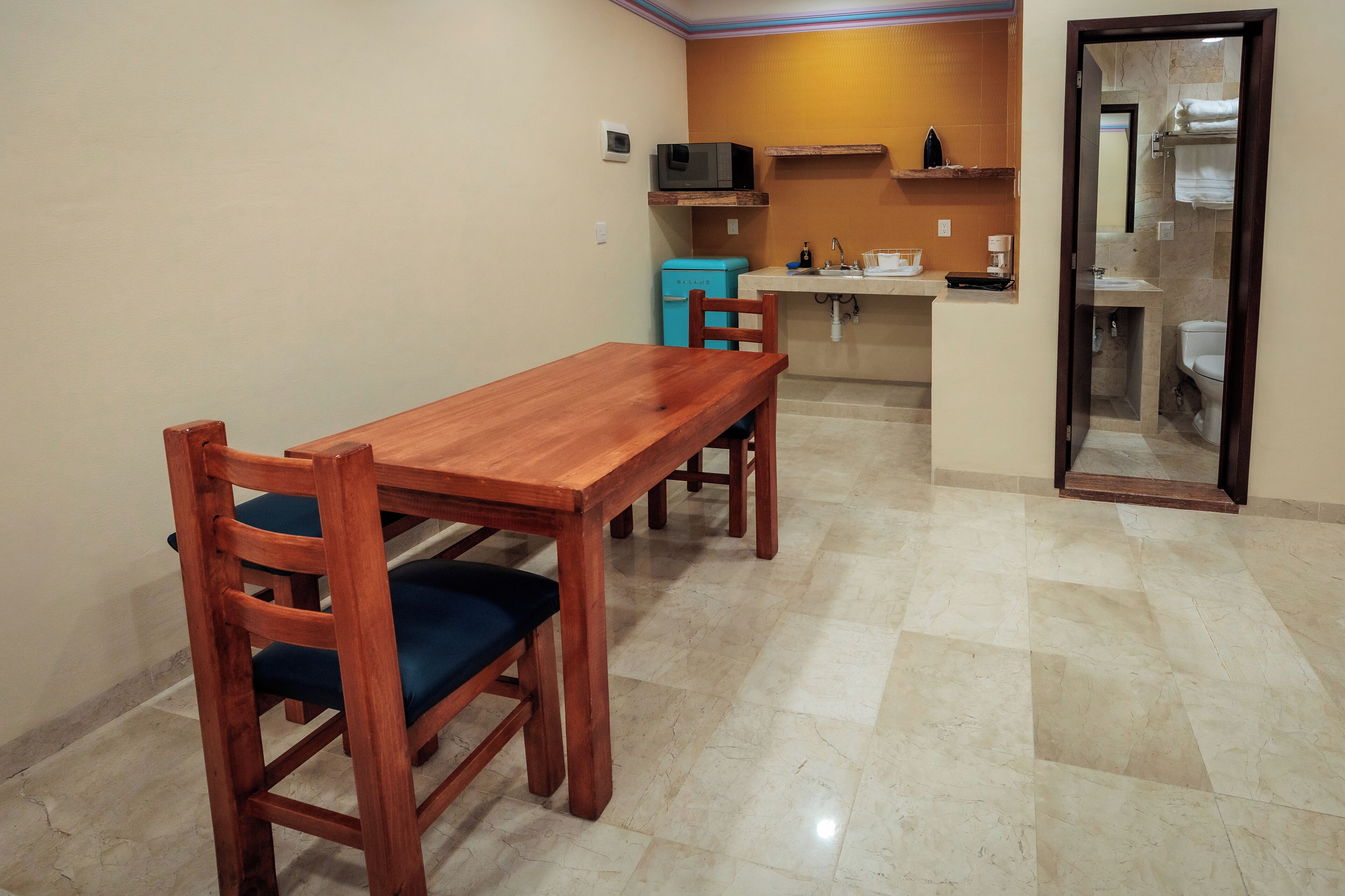 Cocina compacta con microondas, fregadero y refrigerador pequeño.