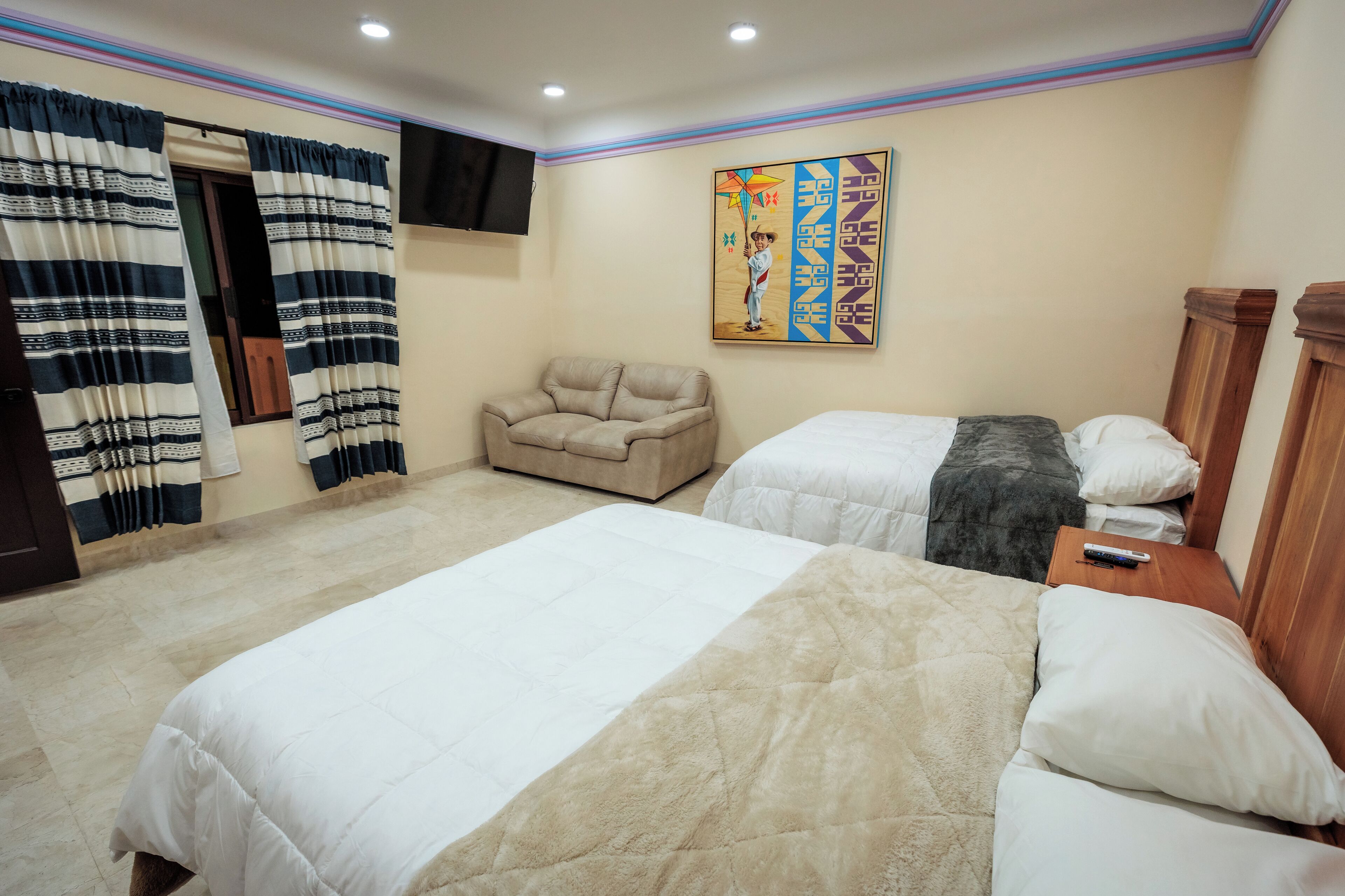 Un dormitorio con dos camas, un sofá, un televisor y un cuadro en la pared.