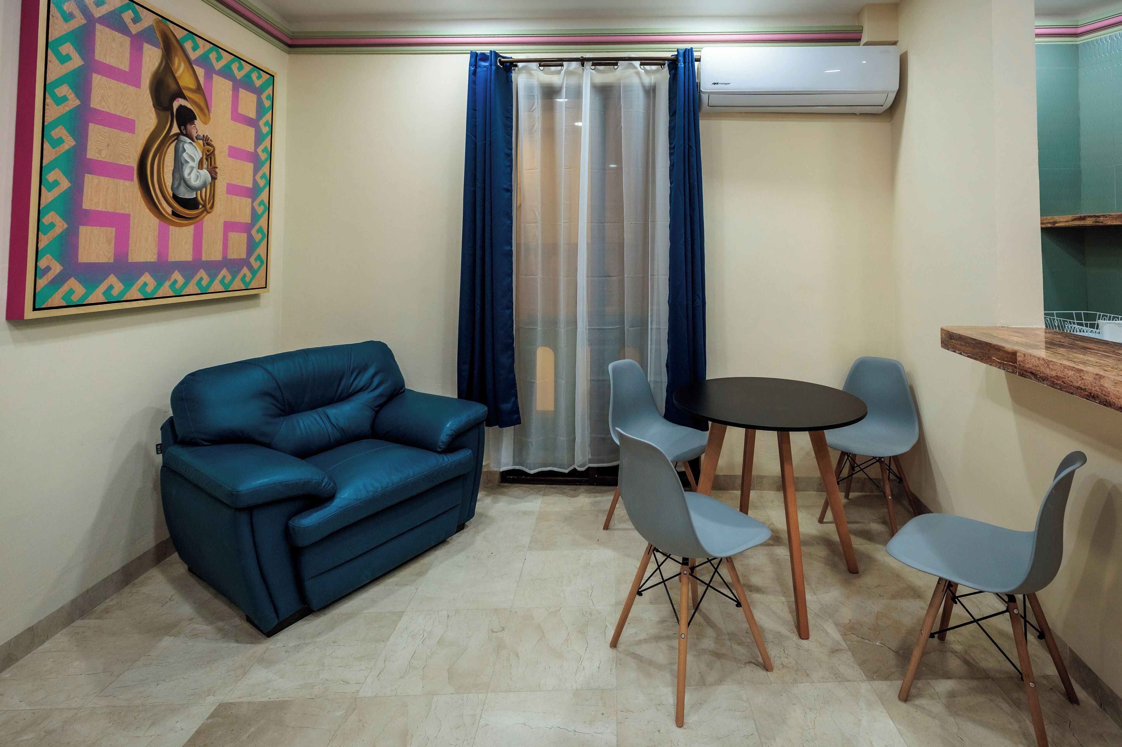 A living room with a blue sofa, a small round table, and four chairs.