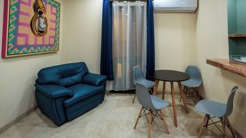 A living room with a blue sofa, a small round table, and four chairs.