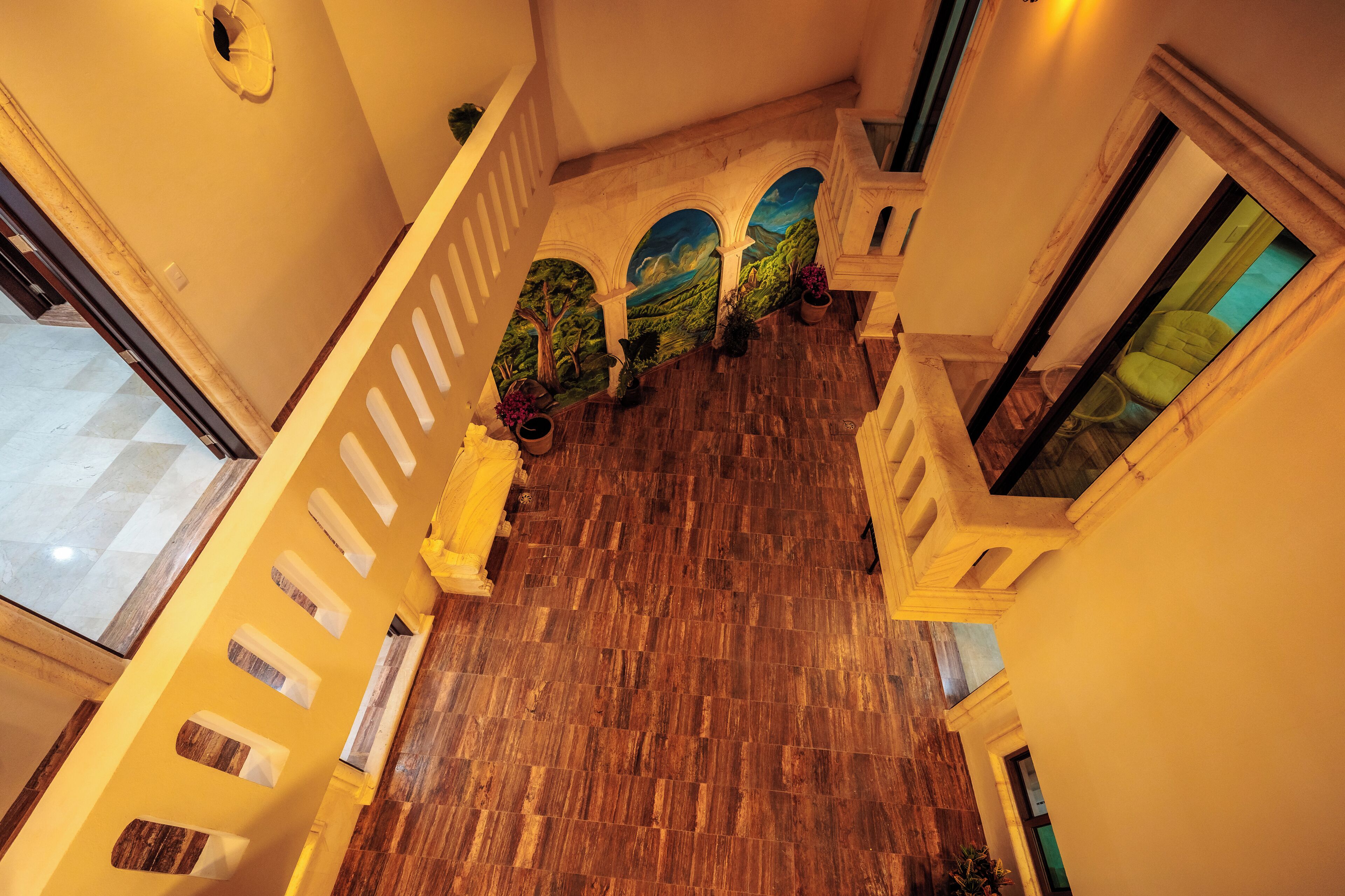 A grand staircase with a wooden floor, white railings, and a mural depicting a landscape.