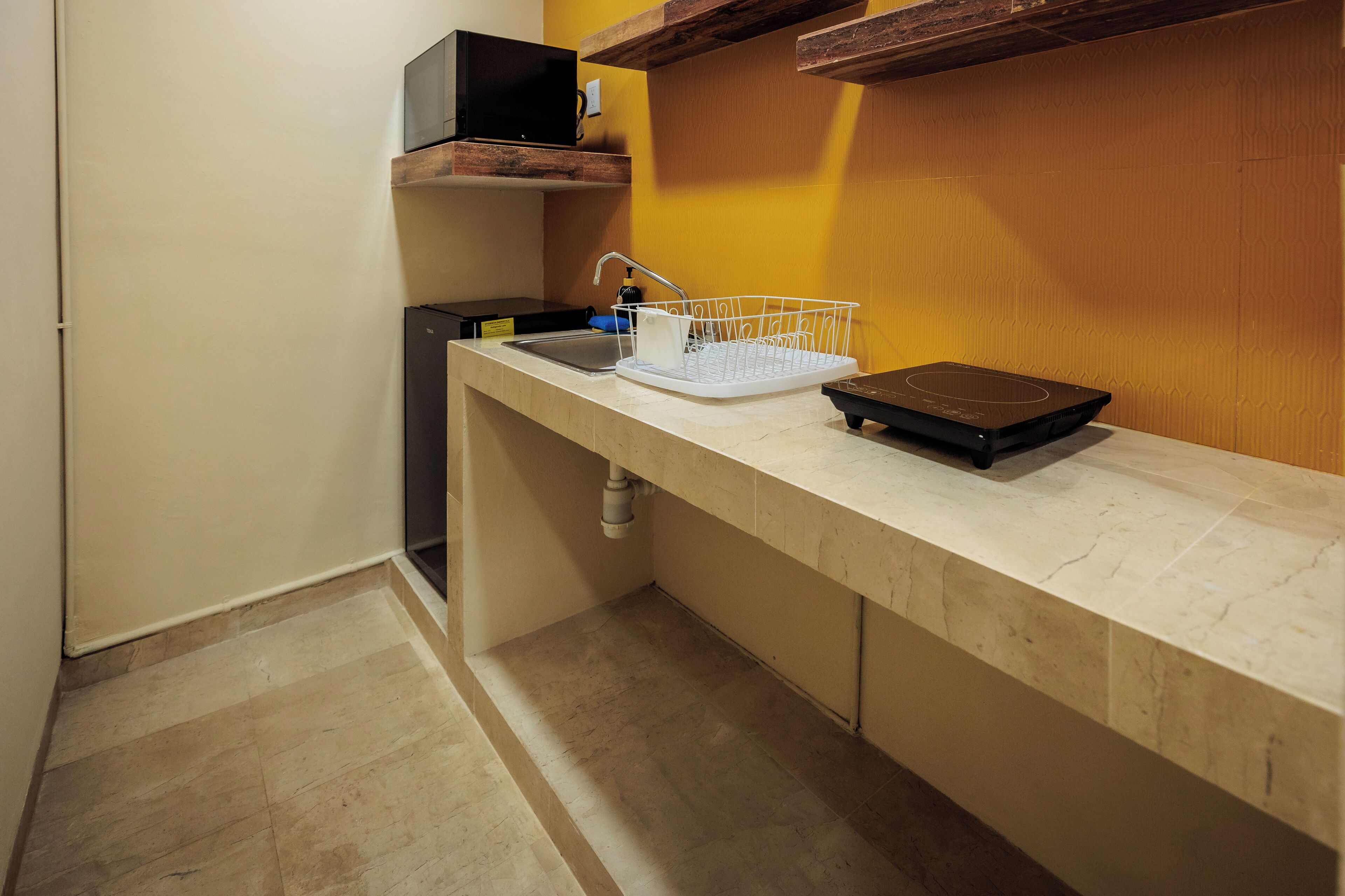 Una cocina con mostrador, pileta, escurreplatos, microondas y tostadora.