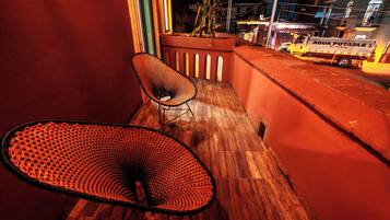 A balcony with a wooden floor, a black mesh chair, and a potted plant.