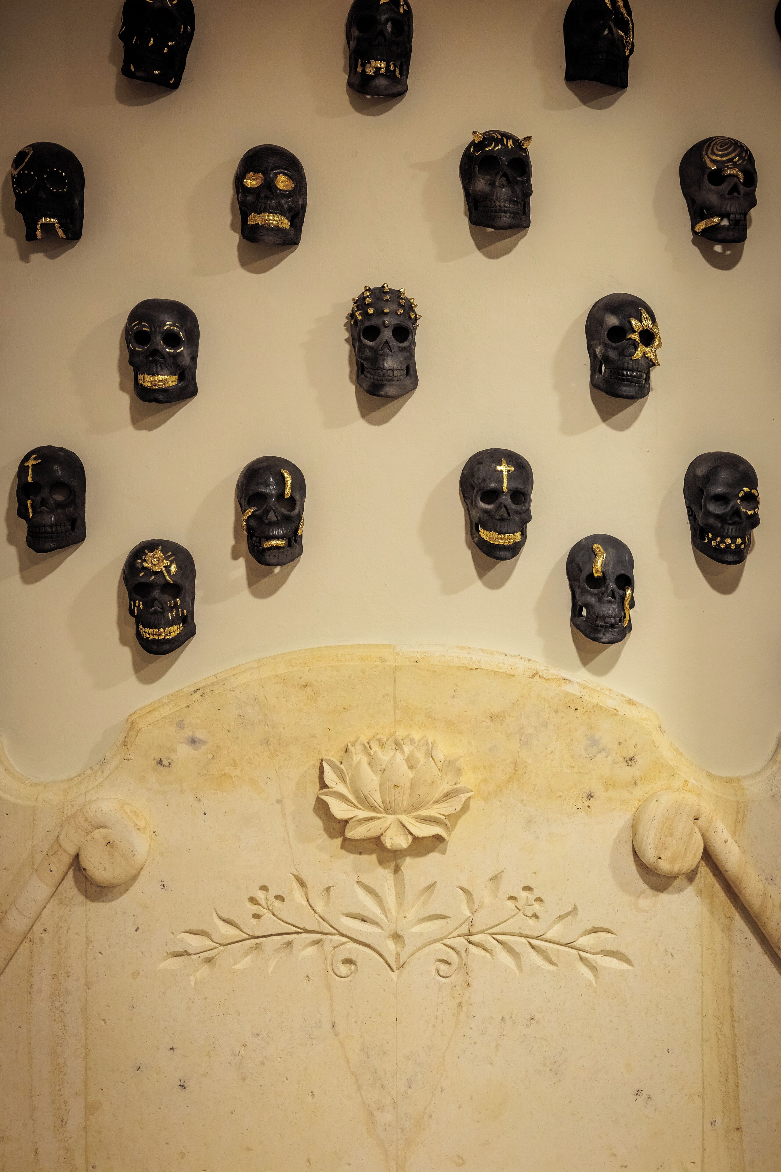 A wall with multiple skull decorations and a carved floral design on a headboard.